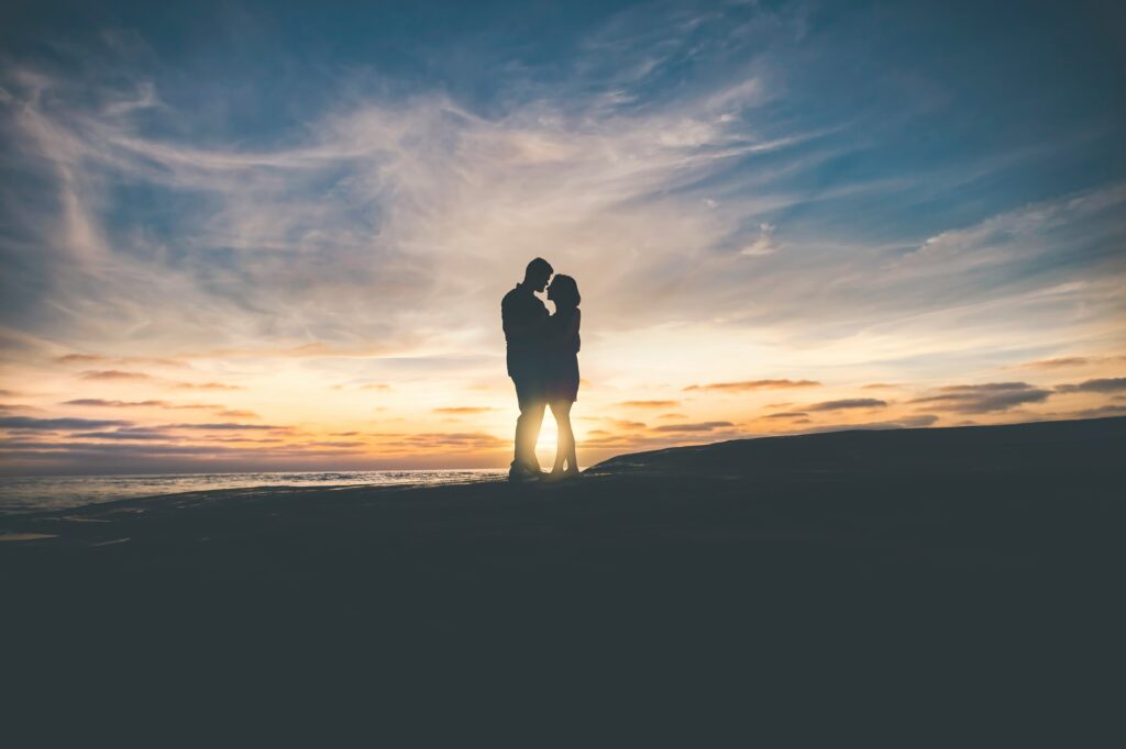 Die Silhouette eines Paares am Meer im Sonnenuntergang als Symbol für die gemeinsame Lösung für Beziehungsprobleme Kiel.