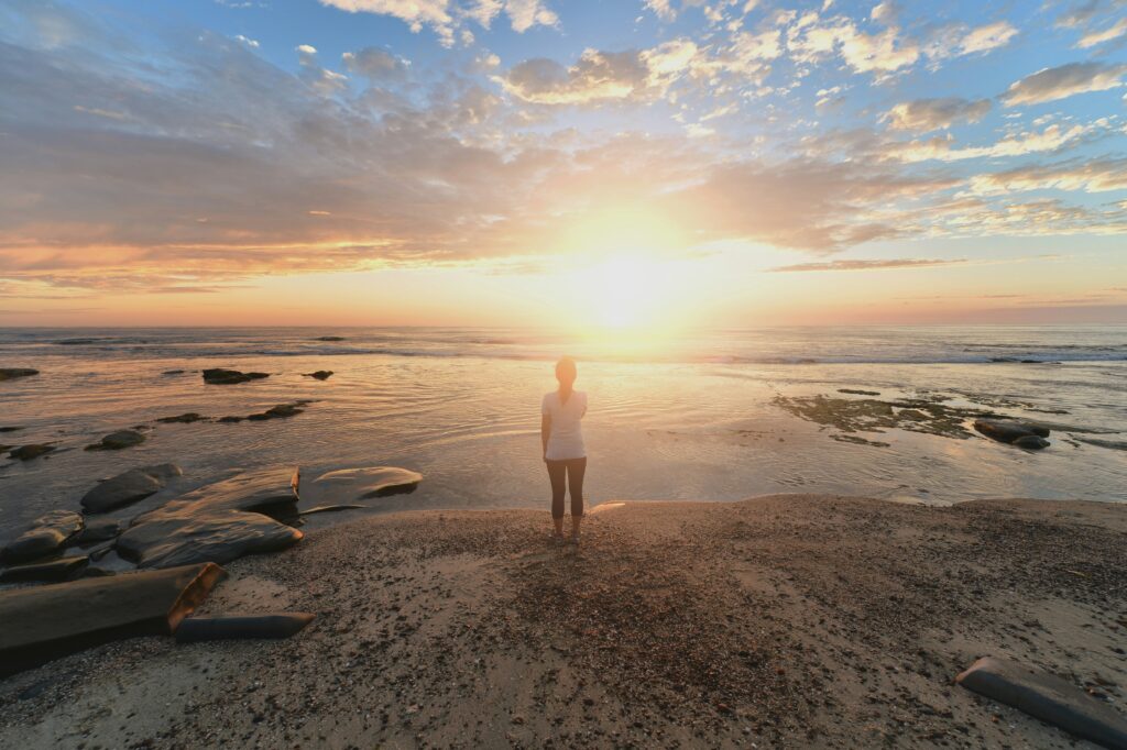 Eine Person blickt am Strand in den Sonnenuntergang und findet neue Wege in der Kindheitstrauma Therapie Kiel.