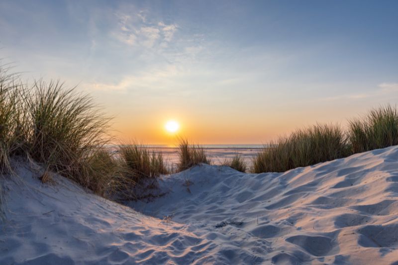 Eine friedliche Dünenlandschaft am Meer im Sonnenuntergang als Symbol für innere Ruhe und neue Perspektiven in der Traumatherapie in Kiel.
