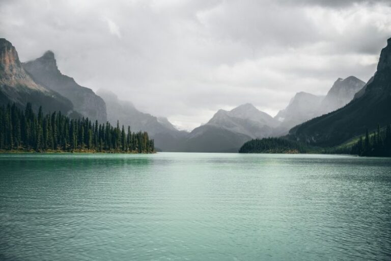 Ein ruhiger Bergsee umgeben von dichten Wäldern und nebelverhangenen Bergen, der die emotionale Stille und den Weg zur Hilfe bei Depressionen in Kiel symbolisiert.