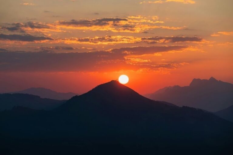 Ein kraftvoller Sonnenaufgang hinter einer dunklen Bergsilhouette, der das Aufbrechen alter Blockaden und die Rückkehr der Lebensenergie durch eine fundierte körperorientierte Psychotherapie in Kiel symbolisiert.